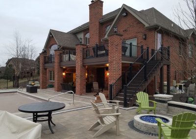 Second story composite deck build covering patio below with staircase, integrated lighting and black railings