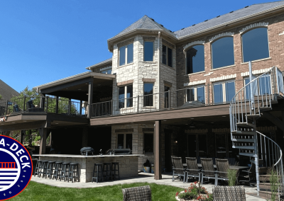 large second story composite deck with spiral staircase to lower patio with outdoor kitchen and multiple seating areas