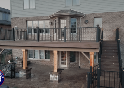 second story composite deck covering patio below with outdoor stairway and integrated lighting